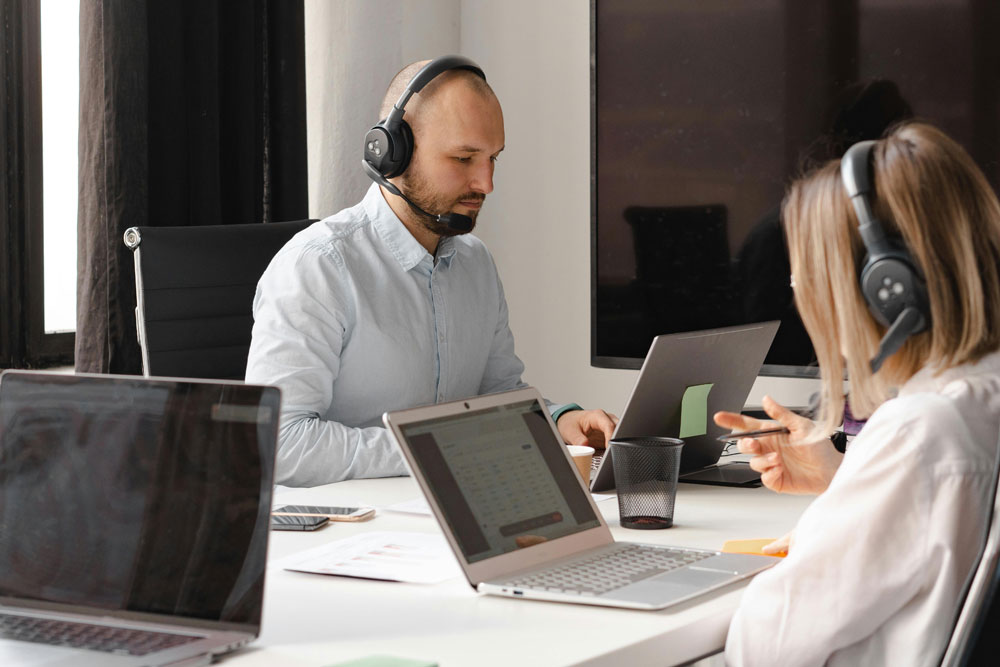 two young persons sat in an office taking calls