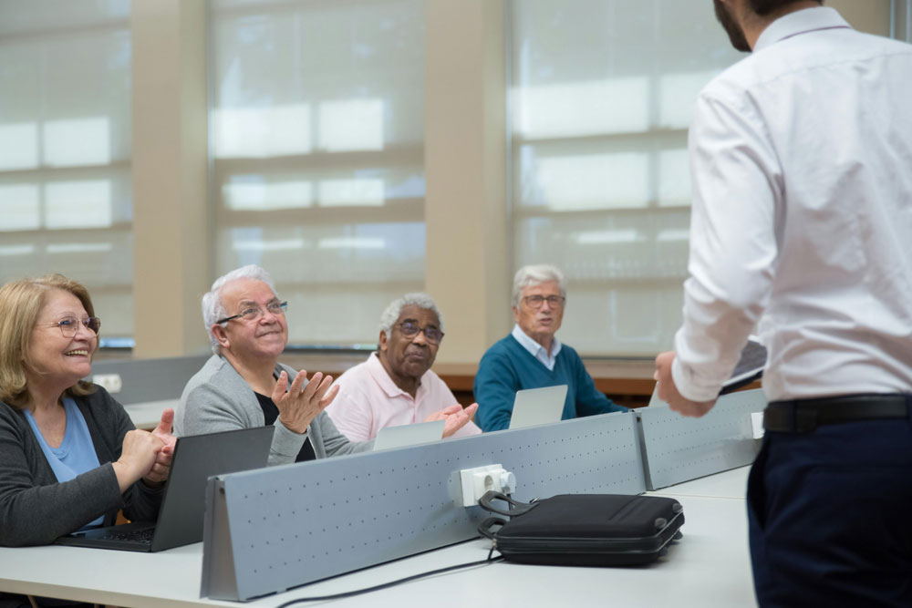 elderly people sat in room getting taught by man